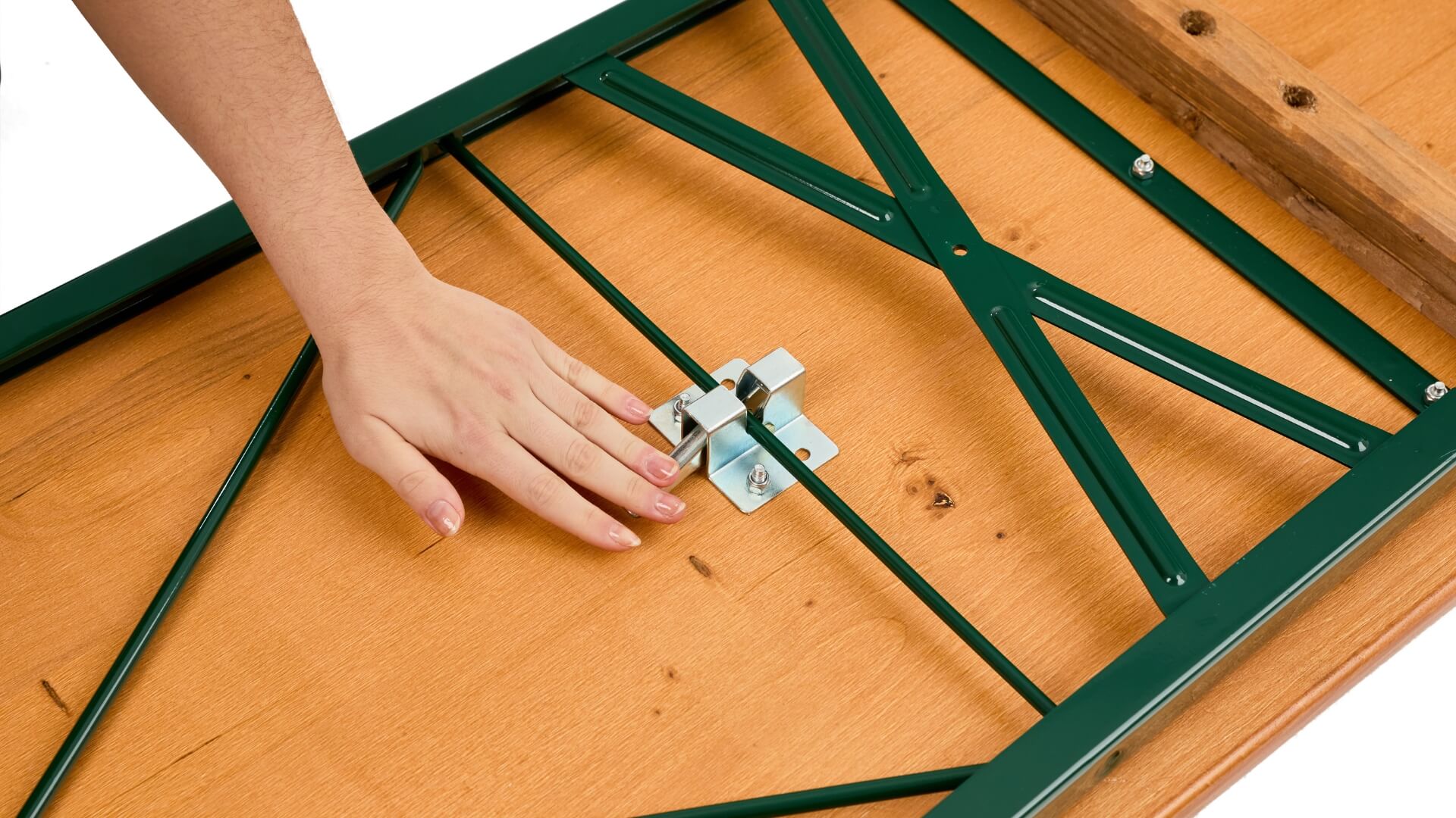A hand pushes down the lever of the folding furniture lock to assemble the classic beer garden table set.