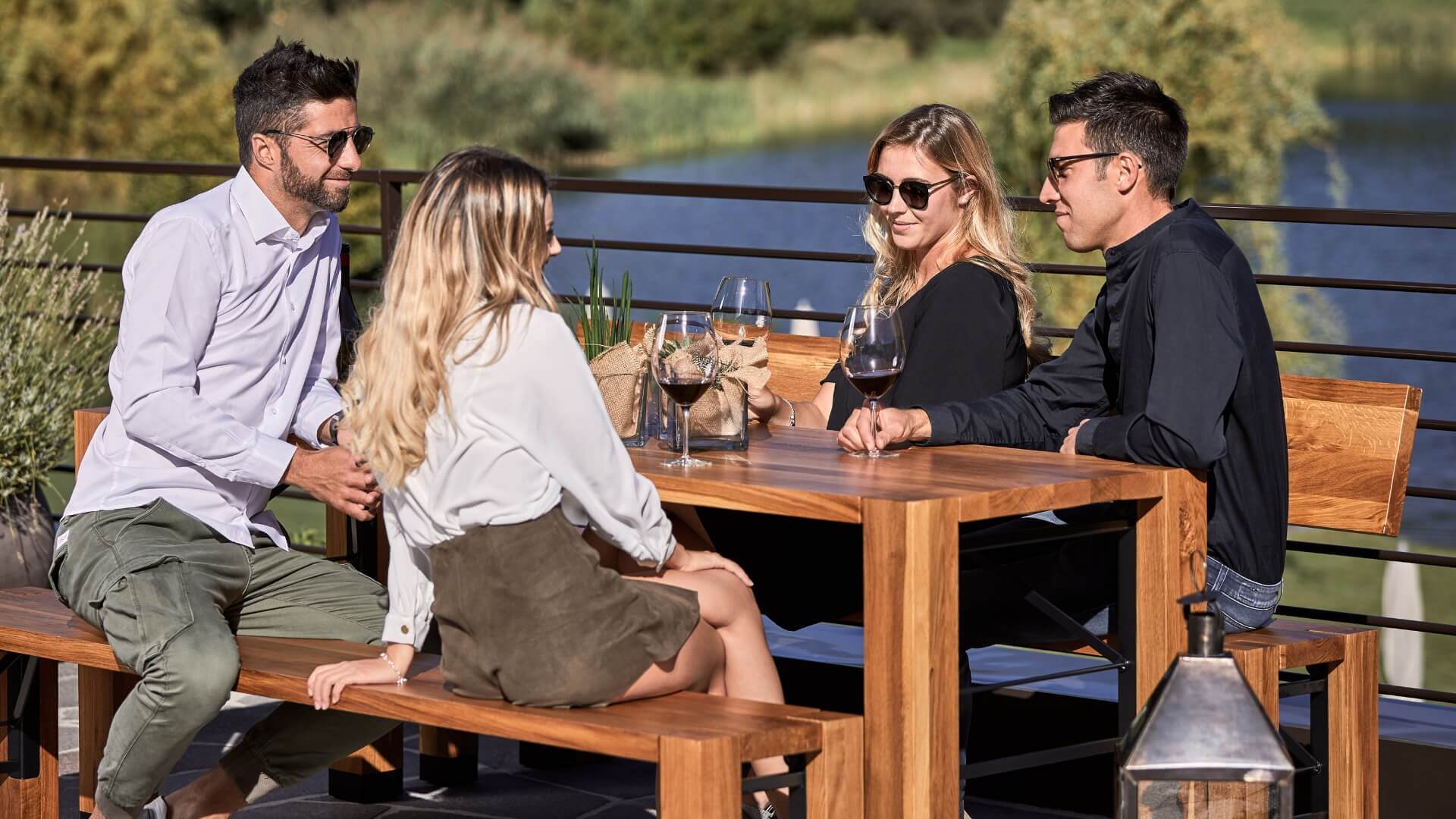 Auf einer Terrasse genießen vier Personen einen sonnigen Tag auf der Designgarnitur Lago.