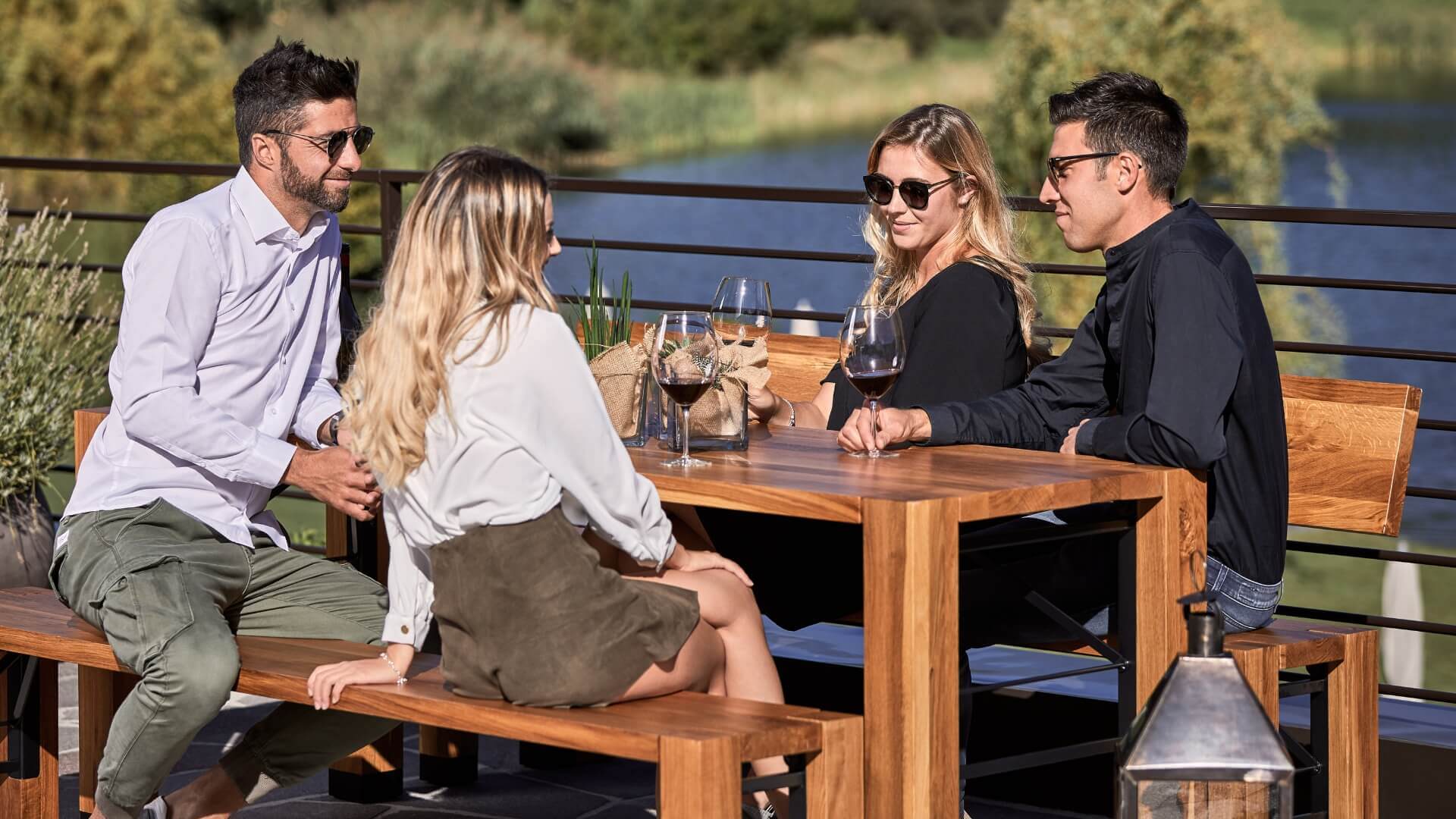 On a terrace four people enjoy a sunny day on design set Lago.