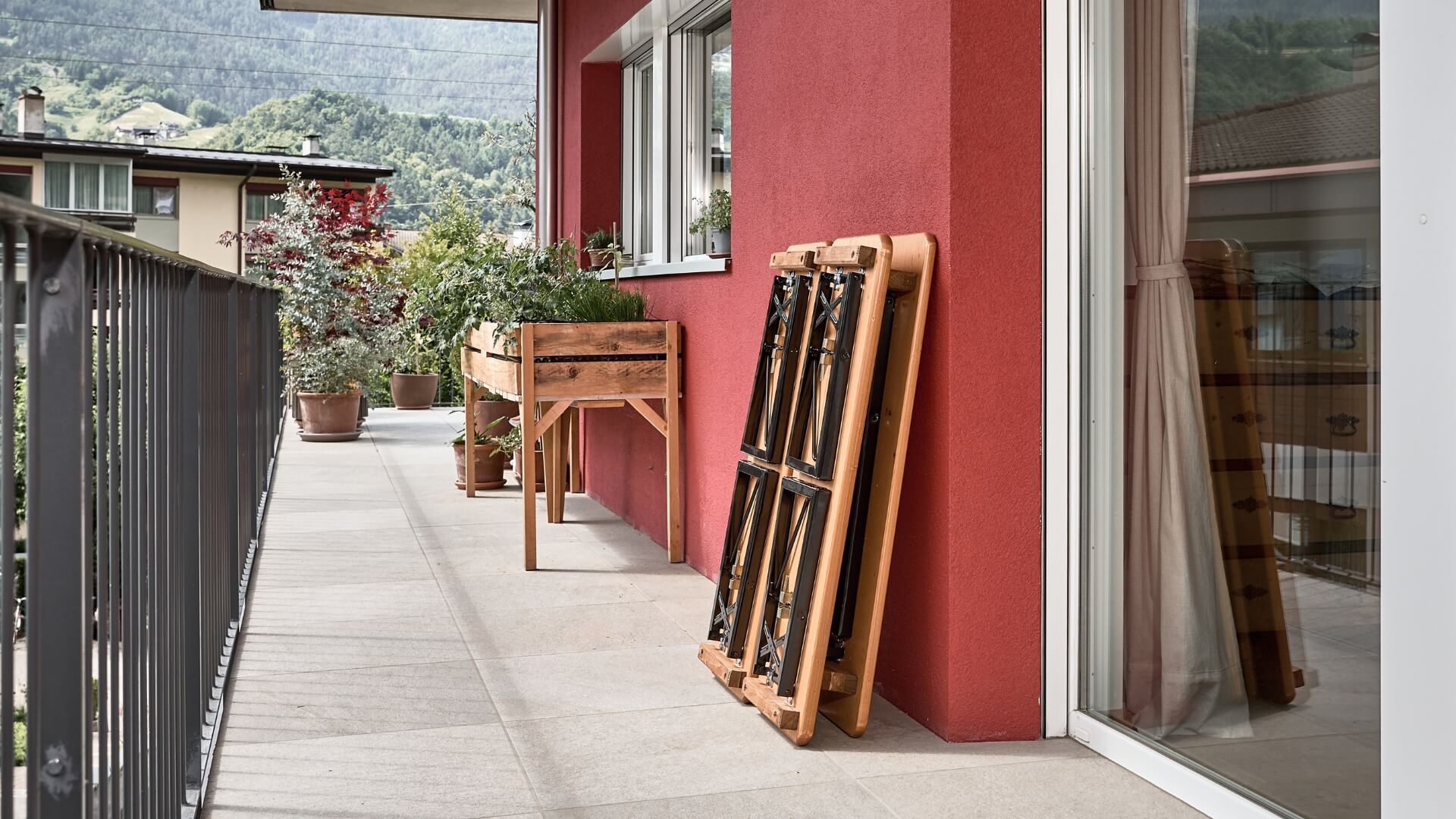 Auf einem Balkon ist die kleine Bierzeltgarnitur Shorty zusammengeklappt und gegen die Wand gestellt.