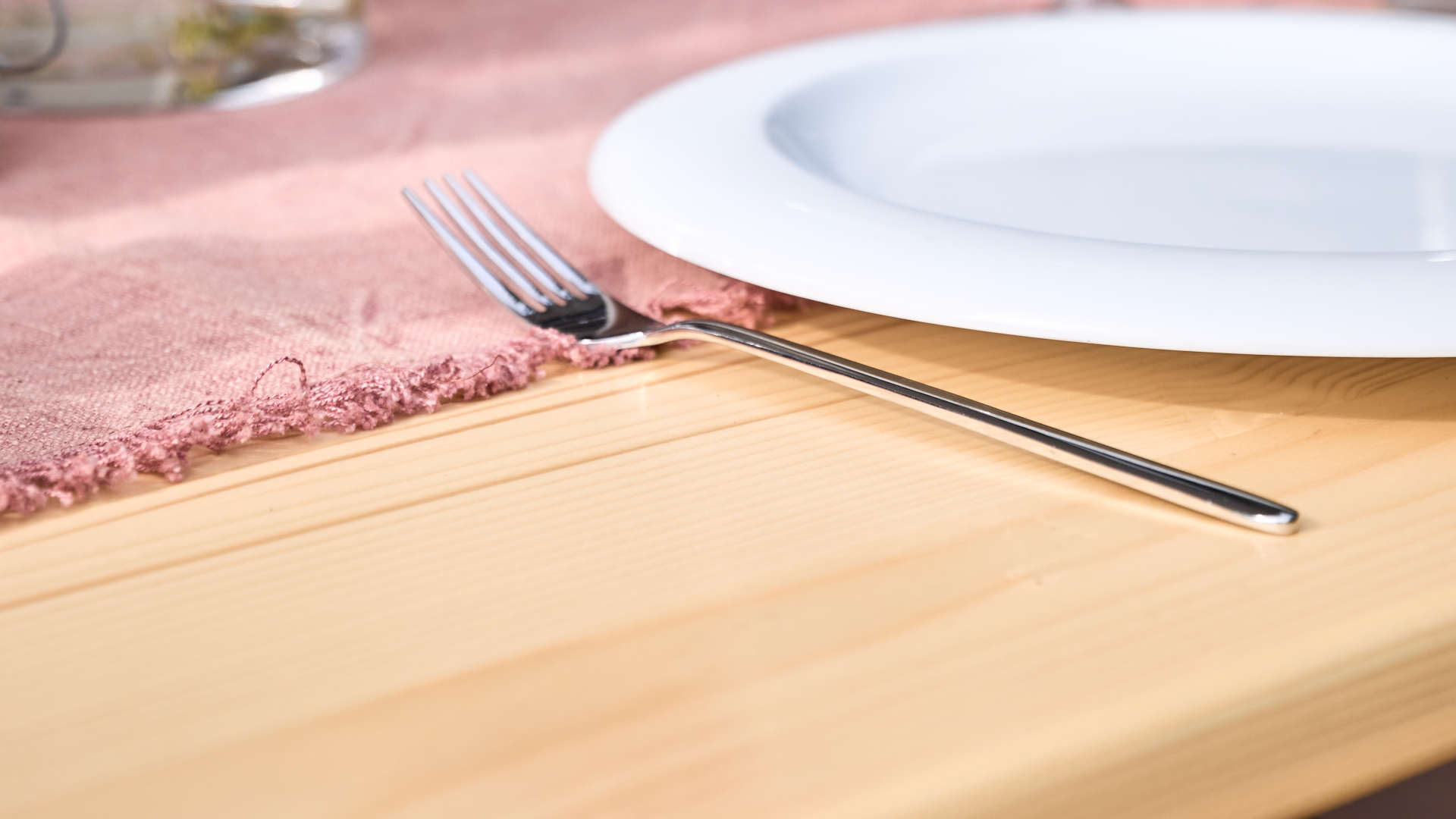 The wide beer garden table set in nature is set. A detail shot showing fork, plate and tablecloth.