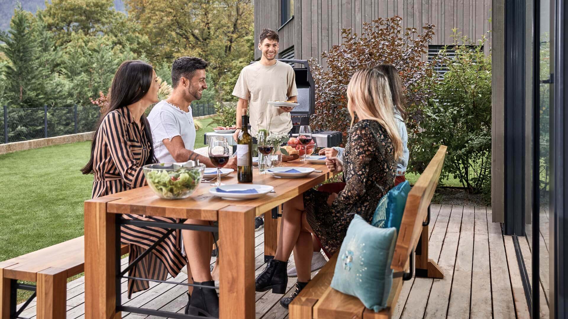 Auf der Terrasse essen fünf Personen auf der gedeckten Designgarnitur Lago.