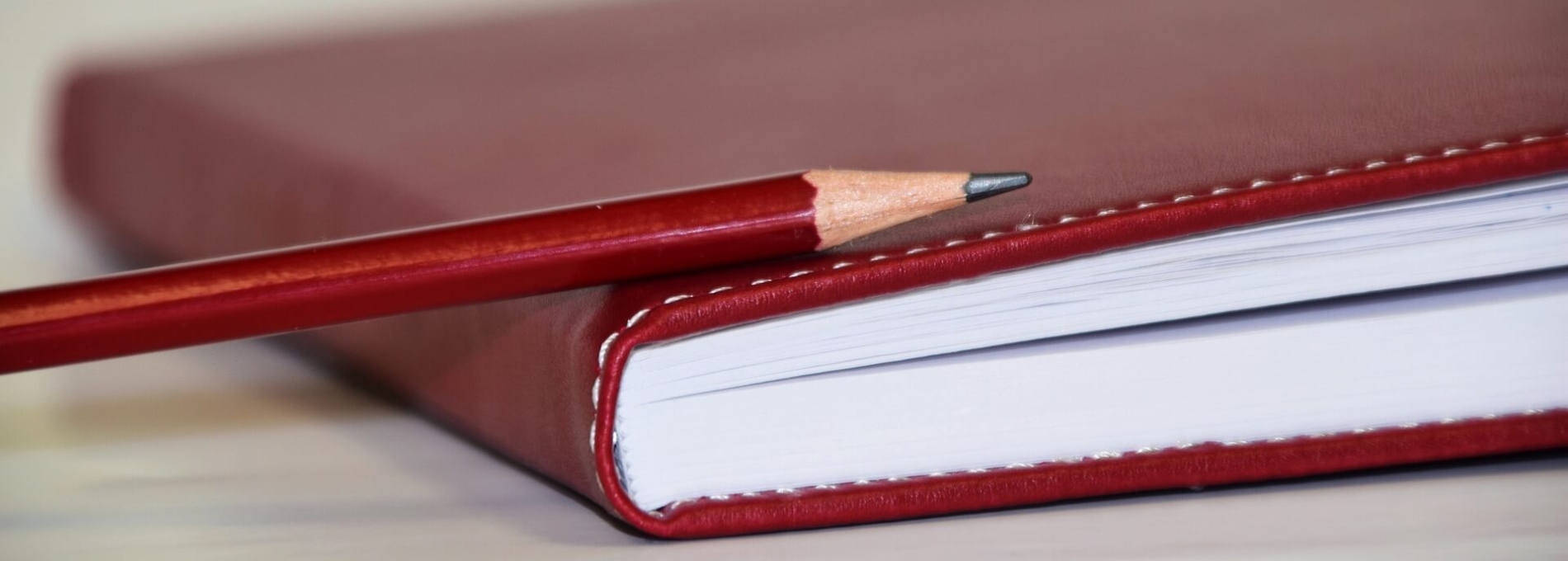 A red pencil lies on a red book.