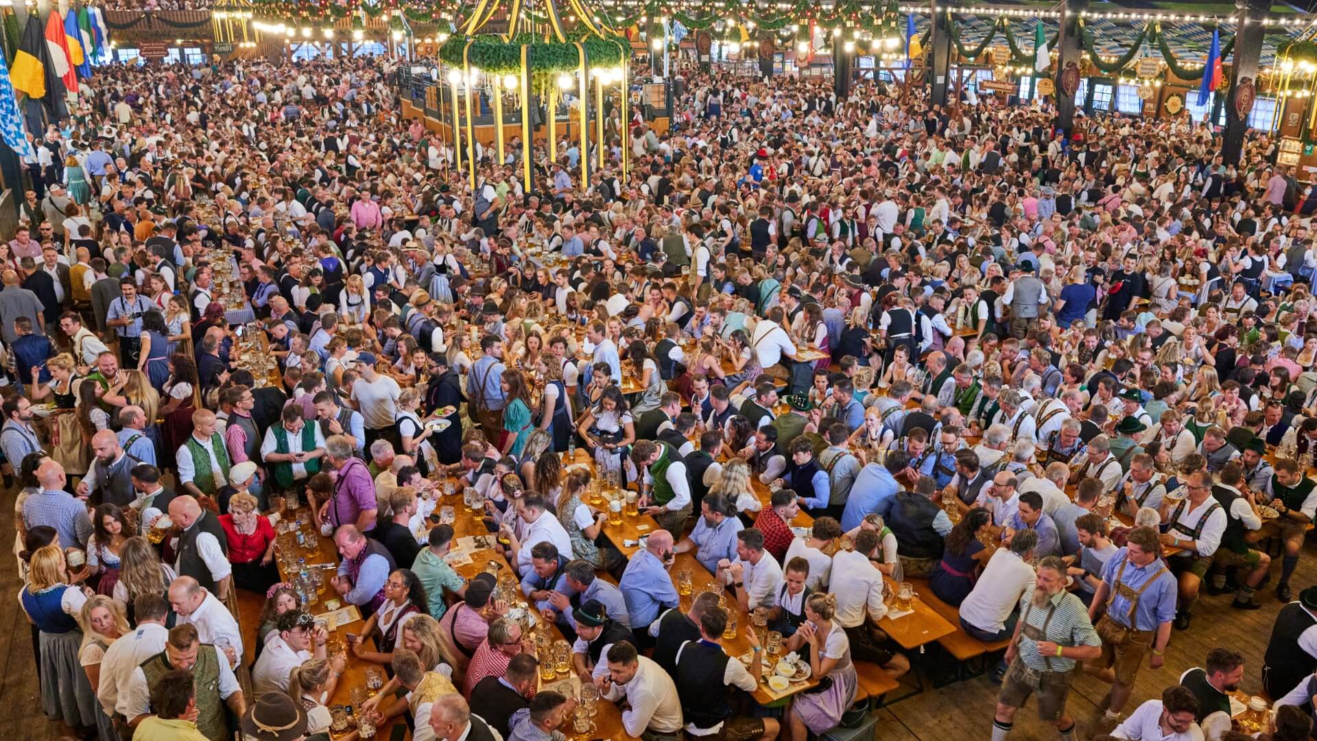 At the Oktoberfest, people sit on the beer garden table sets with leg room.