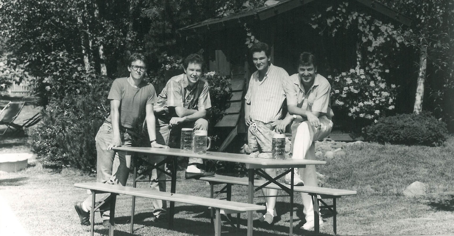  4 people are standing next to a beer table set and this photo is associated with the start of production of beer table sets in 1986.