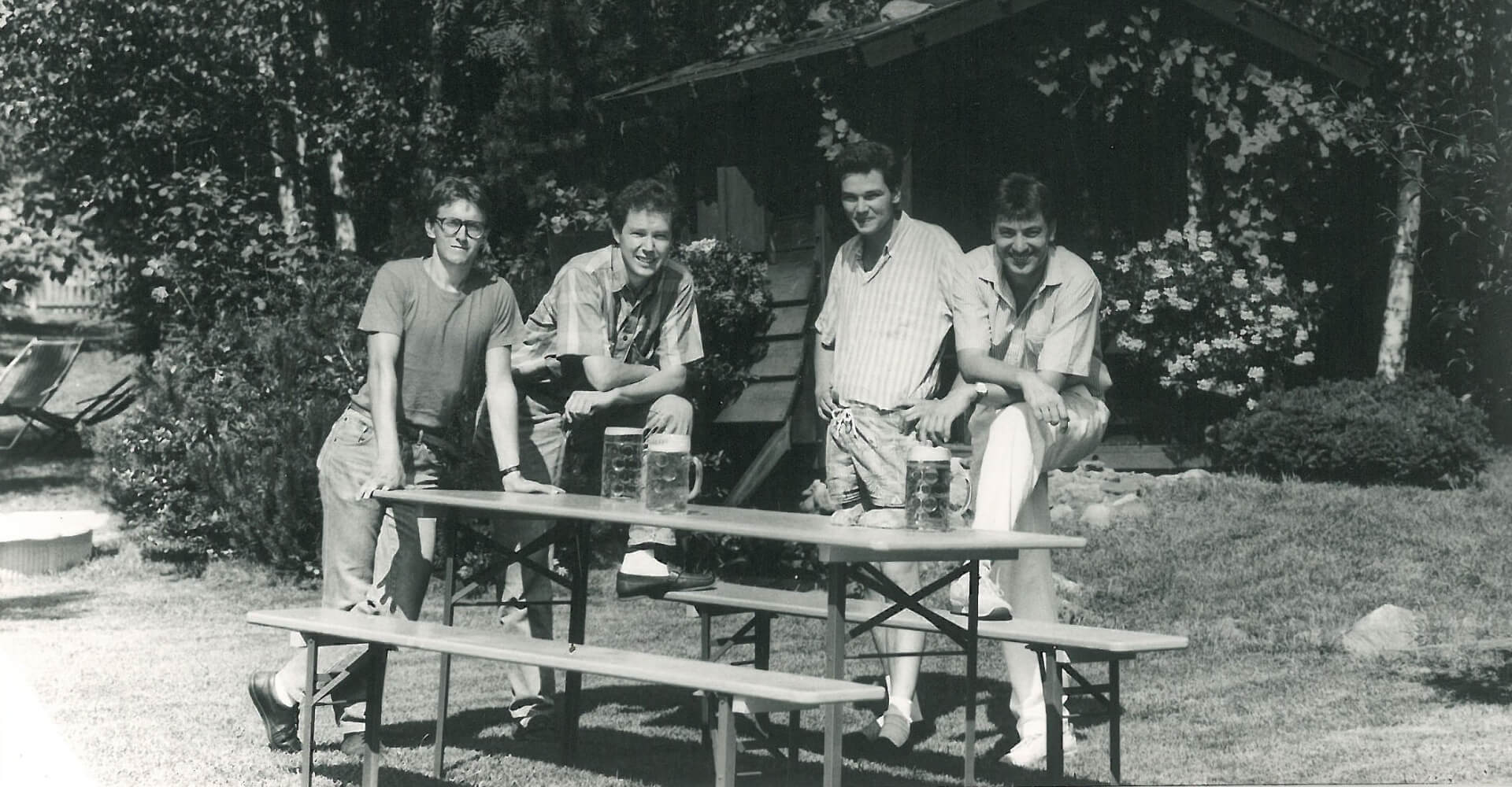 Start der Produktion von Tisch- und Bankfüßen im Jahre 1986 4 Personen stehen neben einer Bierzeltgarnitur und dieses Foto verbindet man mit dem Beginn der Produktion der Bierzeltgarnituren im Jahre 1986..
