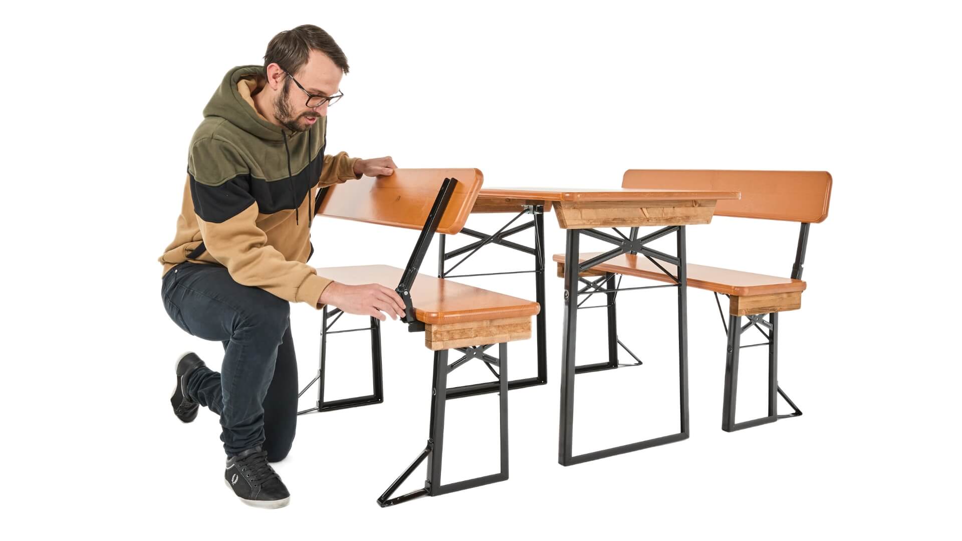 A boy presses the bolt at the backrest of the small beer garden table set to be able to fold the backrest.