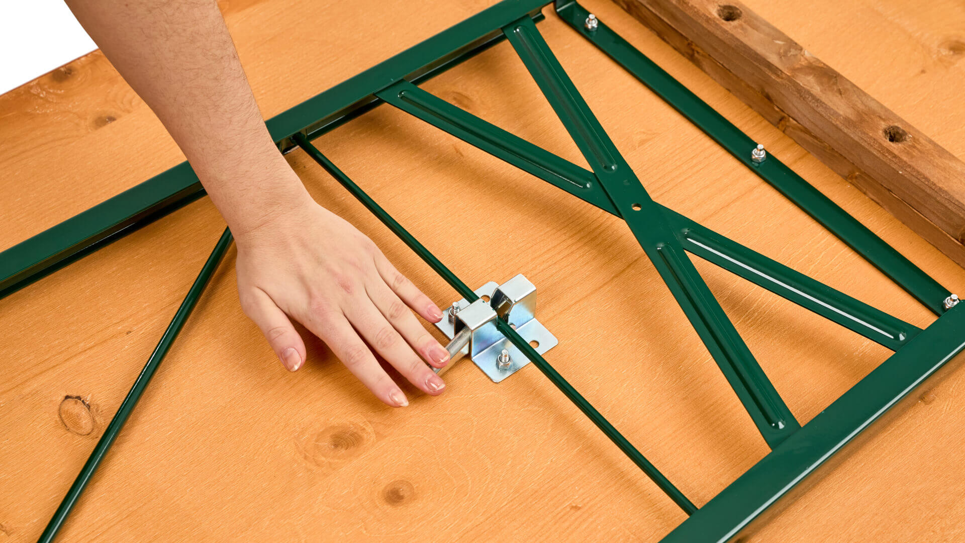 One hand pushes down the lever of the folding furniture lock to assemble the wide beer garden table set.