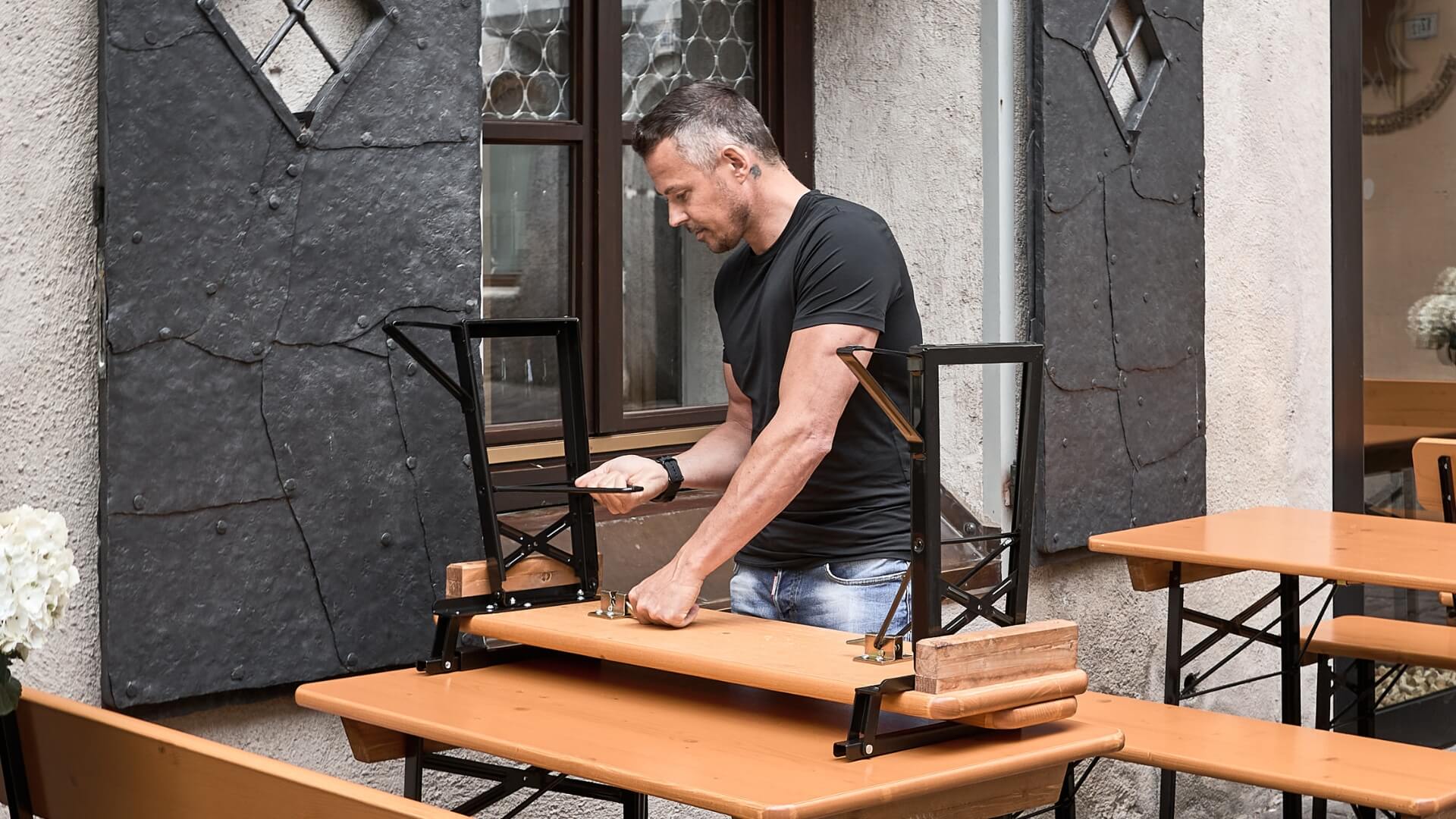 A man dismantles the small beer garden table set "Shorty" to store it.