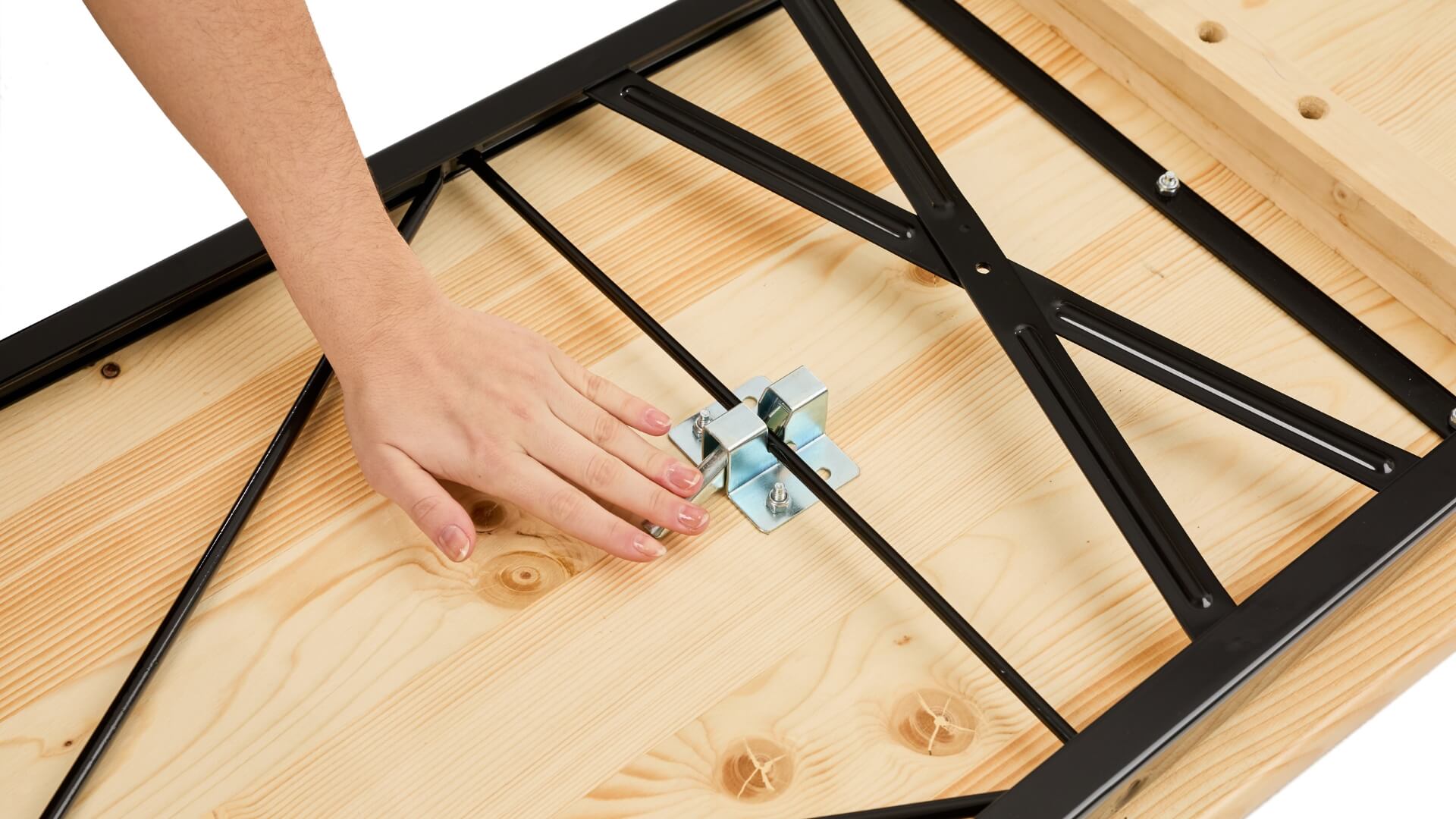 A hand pushes down the lever of the folding furniture lock to assemble the classic beer garden table set.