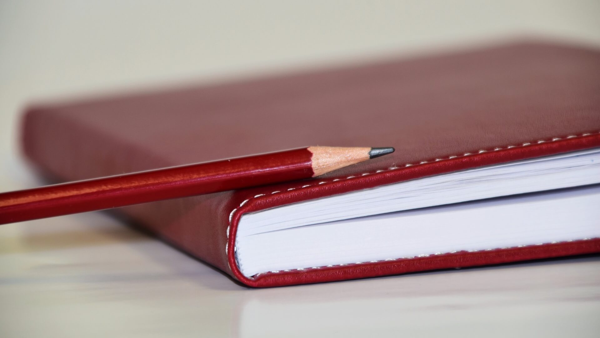 A red pencil lies on a red book.