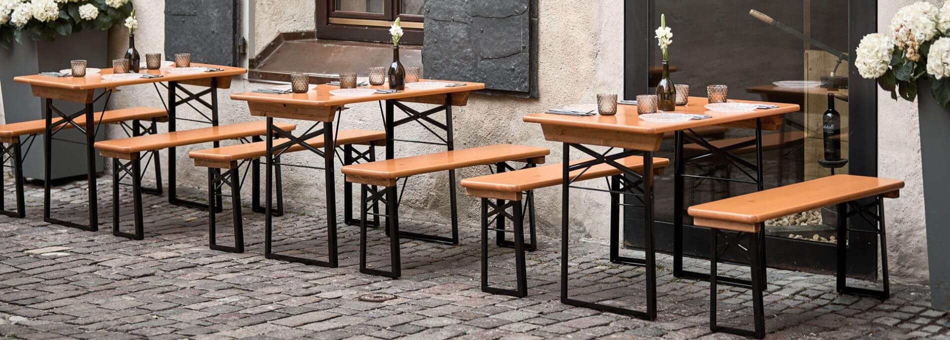 Several small beer garden table sets were placed in an outdoor area.