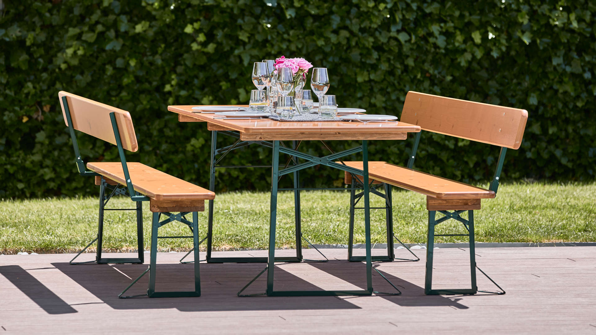 Wide beer garden table set with backrest in pine stands covered on the terrace.
