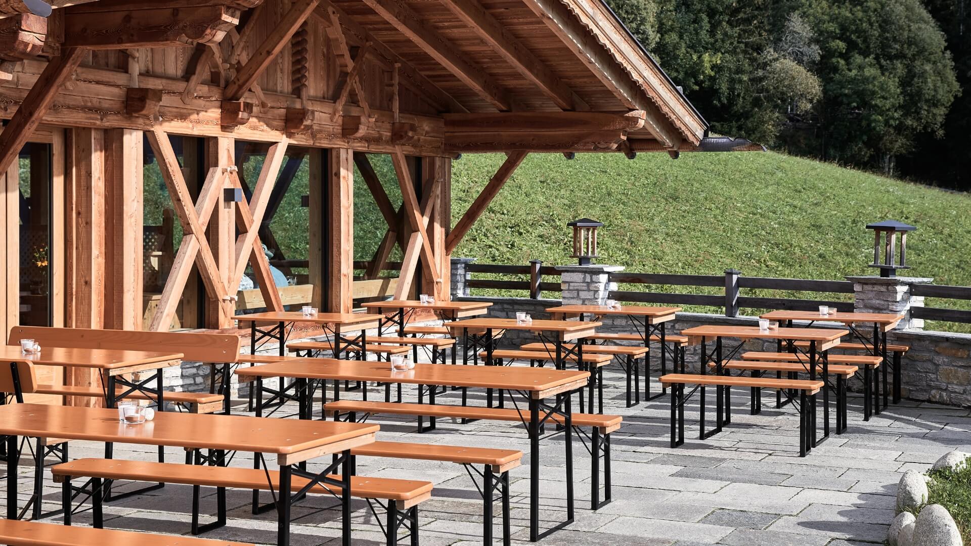 Various beer garden table sets have been set up on an alpine pasture.