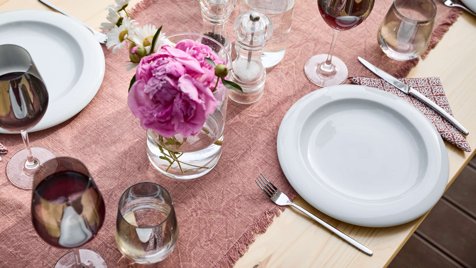 The wide beer garden table set with backrest was covered with plates, glasses, cutlery and decorations.