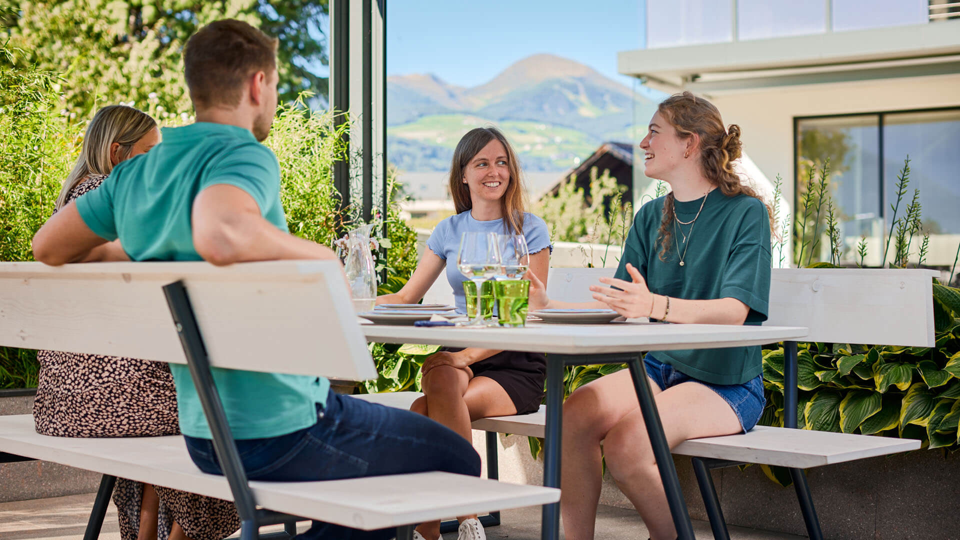 Vier Personen sitzen im Garten auf der Designgarnitur Riva und unterhalten sich.