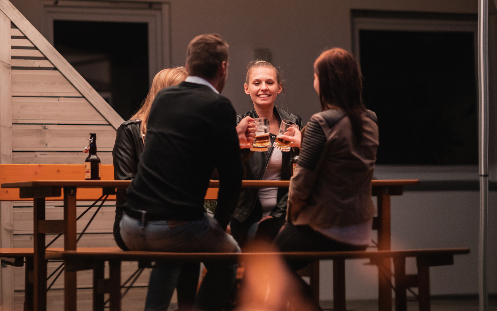 Vier Personen sitzen im Garten auf der Designgarnitur Rustica und genießen ihr Bier.