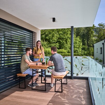 Freunde sitzen gemeinsam auf der kleinen Bierzeltgarnitur Shorty ohne Lehne und genießen Getränke auf der Terrasse.