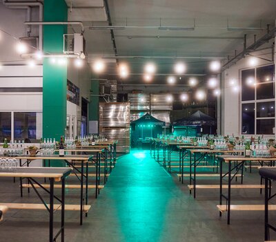 Die Stehtische sind in einer Halle aufgestellt und für ein Catering dekoriert.