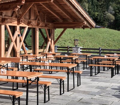 Man sieht den Außenbereich eines rustikalen Restaurants, wo Shorty und Classic Bierzeltgarnituren mit schwarzem Untergestell platziert wurden.