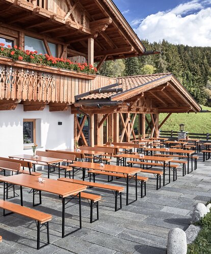Several beer garden table sets are placed on the terrace of a restaurant.