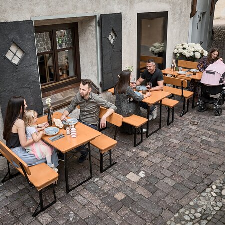 Auf der kleinen, gedeckten Bierzeltgarnitur Shorty mit Lehne sitzen zwei Erwachsene und ein Kind.
