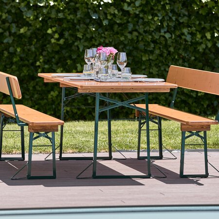 Die breite Bierzeltgarnitur mit Lehne in Kiefer steht gedeckt auf der Terrasse.