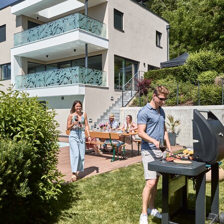 Im Garten findet eine Grillfeier statt und die breite Bierzeltgarnitur mit Lehne dient zum Verweilen.