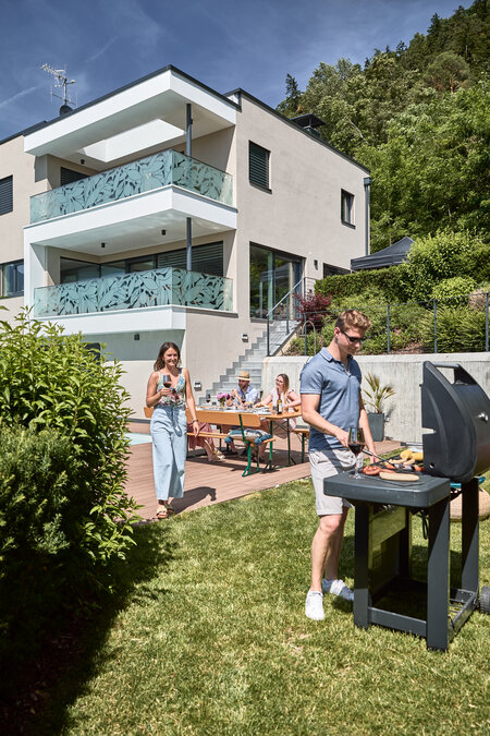 A barbecue party is taking place and the wide beer garden table set with backrest is used to relax.