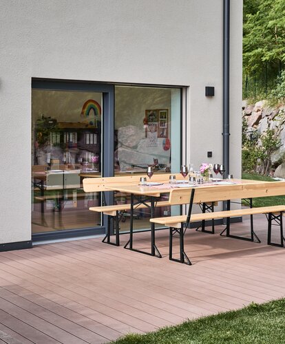 Die Breite Bierzeltgarnitur steht gedeckt auf der Terrasse.