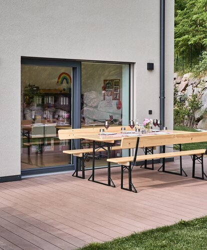 Die Breite Bierzeltgarnitur steht gedeckt auf der Terrasse.