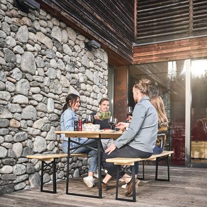 4 Personen genießen Ihre Mahlzeit auf einer Terasse auf der klassischen Bierzeltgarnitur in Natur.