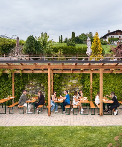 Mehrere Leute haben auf den klassischen Bierzeltgarnituren beim Guggerhof Platz genommen.