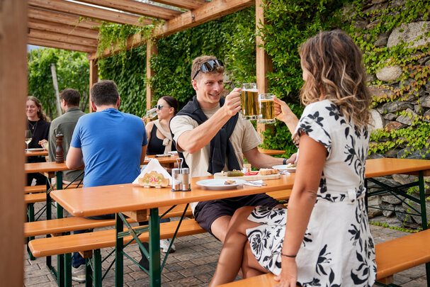 Mehrere Personen genießen auf den klassischen Bierzeltgarnituren die Marende und das Bier beim Guggerhof.