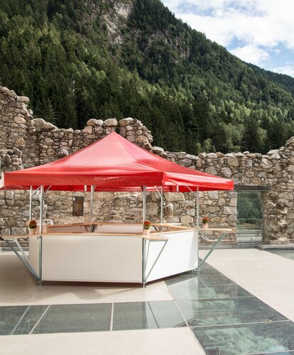 Ein Bierstand mit rotem Dach und weißen Untergestell steht im Freien.