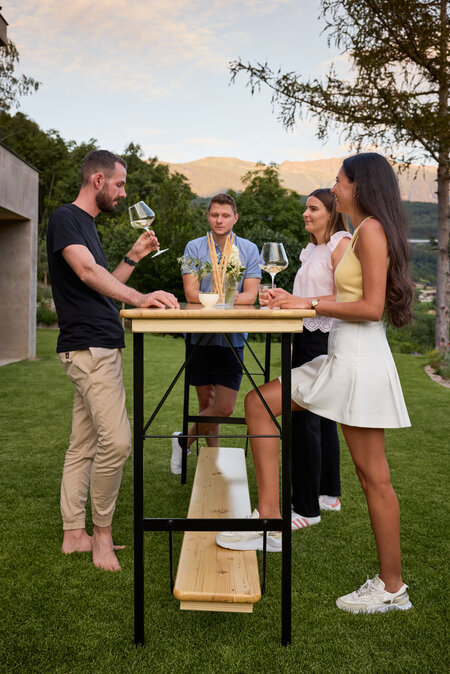 Several people are standing around the Stand Up bar table, chatting and holding glasses.