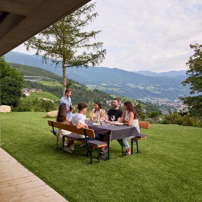 An dem gedeckten Biergartentisch sitzen mehrere Personen und verbringen einen geselligen Abend.