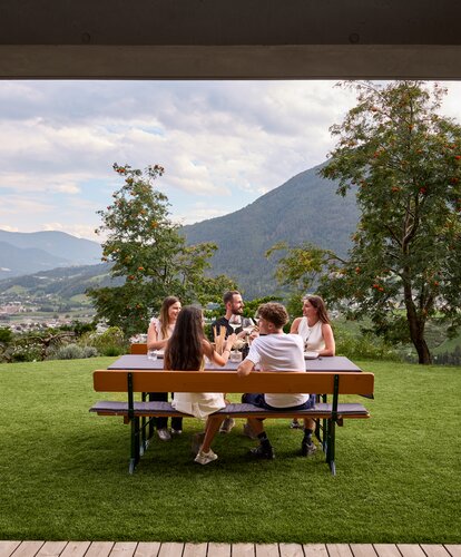 An dem gedeckten Biergartentisch sitzen mehrere Personen und verbringen einen geselligen Abend.