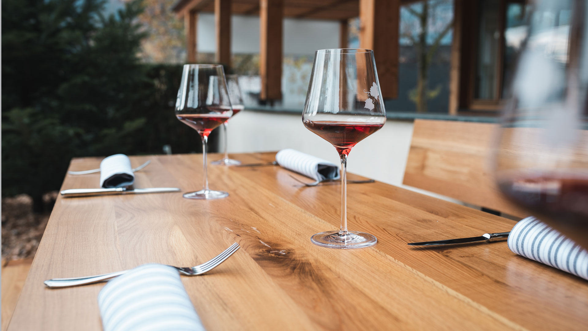 Die Designgarnitur Lago wird in der Gastronomie eingesetzt. Zwei Weingläser und Gedeck sind auf dem Tisch.