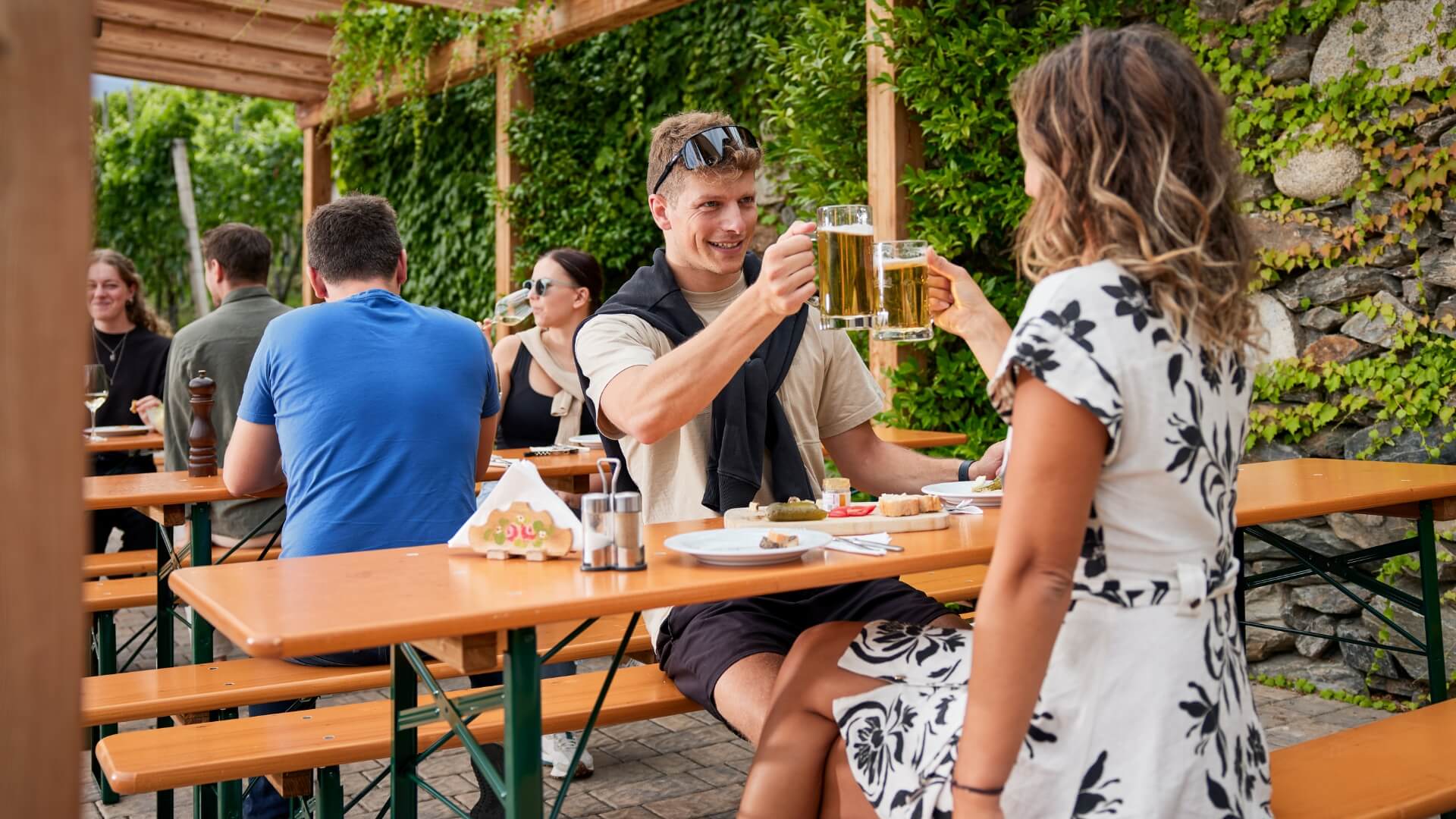 Several people enjoy the Marende and the beer at the Guggerhof on the classic beer garden table sets.