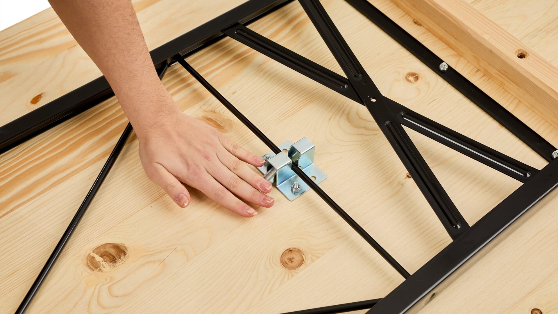 One hand pushes down the lever of the folding furniture lock to assemble the wide beer garden table set.