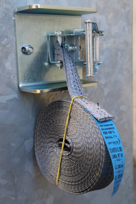 The tensioning strap is attached to the transport container.