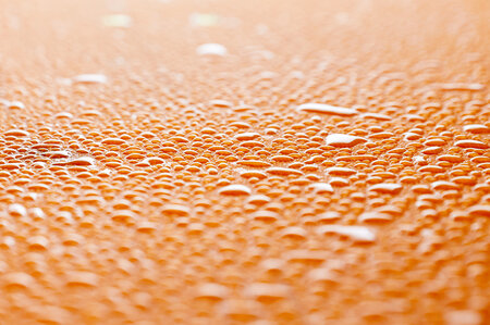 There are many drops of water on the surface of the beer garden table set.