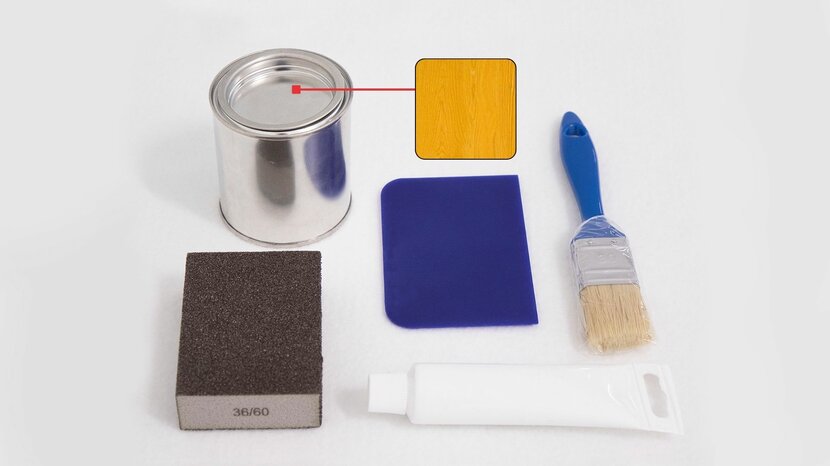 Das Bild zeigt des Inhalt eines Reparaturkits für eine Bierzeltgarnitur in der Farbe Kiefer, bestehend aus 500 ml Lasur (Farbe Kiefer), 75 g Holzkitt, Spachtel, Pinsel, Schleifpapier und einer Anleitung