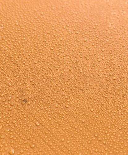 Bierzeltgarnitur mit Wassertropfen auf der Oberfläche des Holzes. Die UV-Lasur schützt die Tischplatte vor Verformungen und Verfärbungen. Das Set ist somit witterungsbeständig und schwer entflammbar.