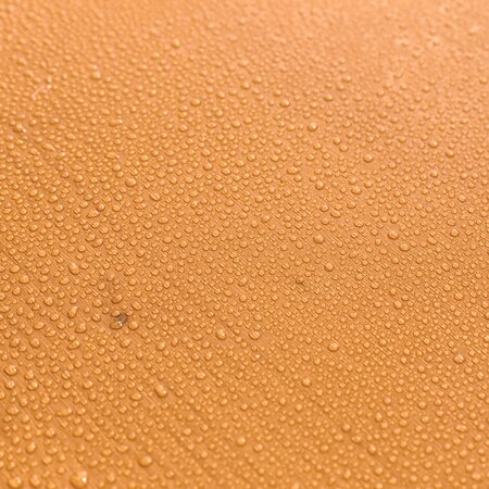 Bierzeltgarnitur mit Wassertropfen auf der Oberfläche des Holzes. Die UV-Lasur schützt die Tischplatte vor Verformungen und Verfärbungen. Das Set ist somit witterungsbeständig und schwer entflammbar.