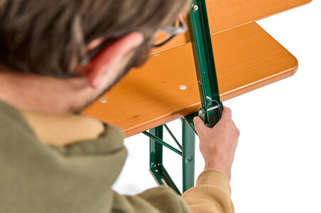A boy presses the bolt at the back of the classic beer garden table set to fold the back.