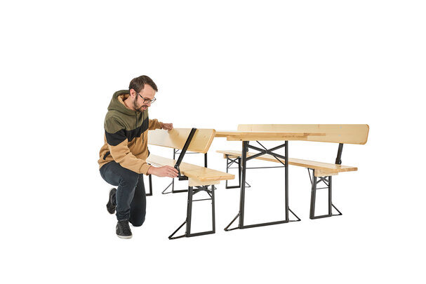 Ein Junge drückt den Bolzen bei der Lehne der klassischen Bierzeltgarnitur, um die Lehne zuklappen zu können.