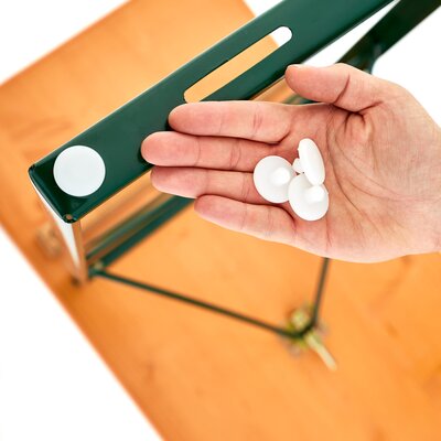 Die angebrachten Kunststoffgleiter an einem Untergestell. Eine Hand hält drei weitere Kunststoffgleiter in das Bild.