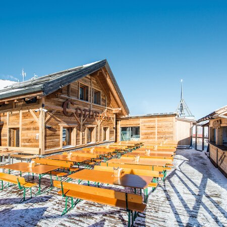 Auf einer Hütte befinden sich im Winter viele breite Bierzeltgarnituren.